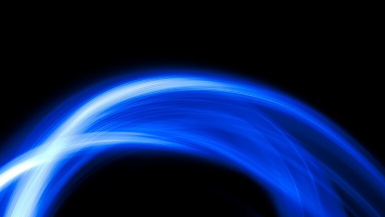 An abstract image featuring a glowing, arcing blue light streak on a black background. The light is brightest and whitest on the left, fading into darker blue as it curves across the frame.